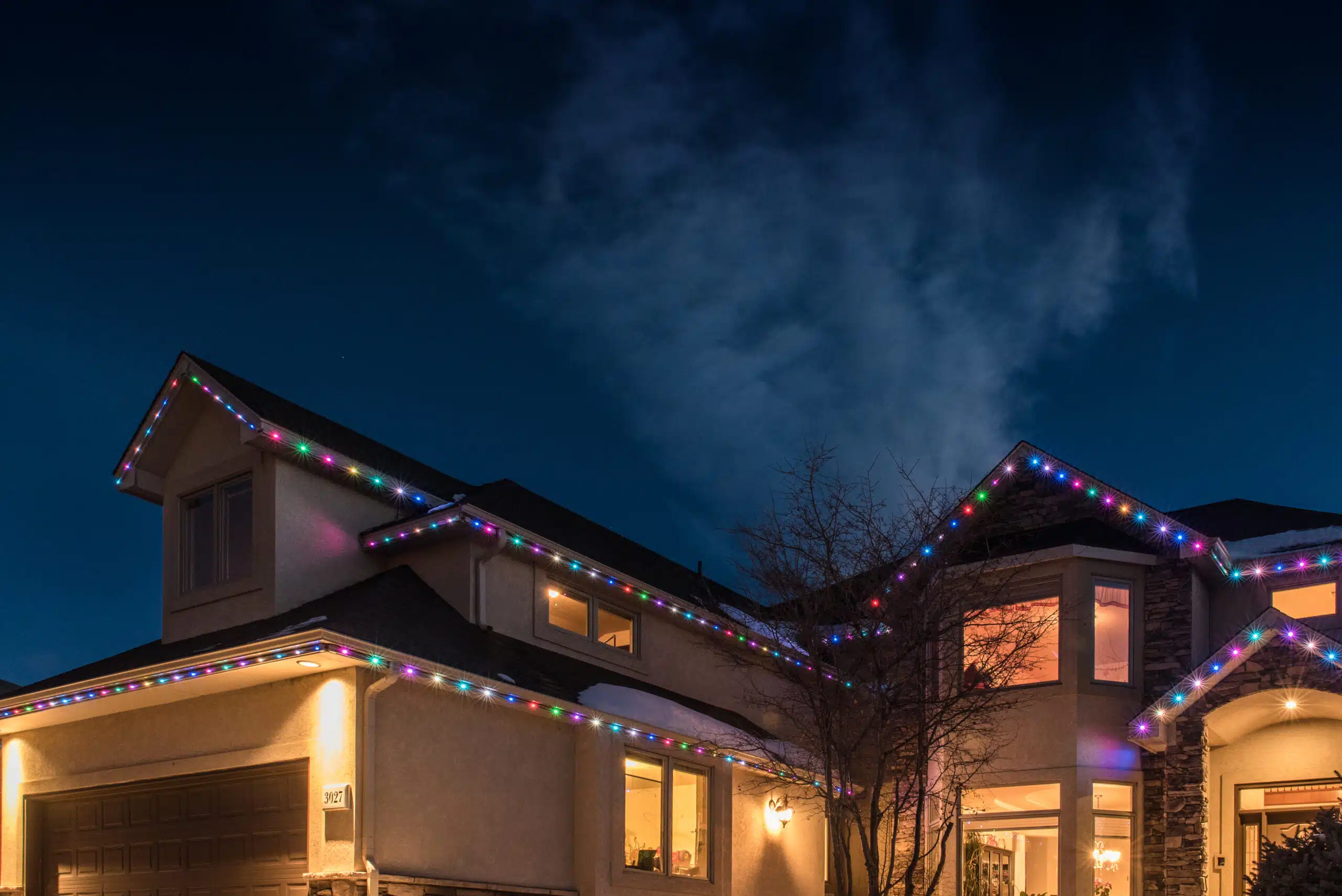 Two storied home decorated with multi-colored LED lights on roofline