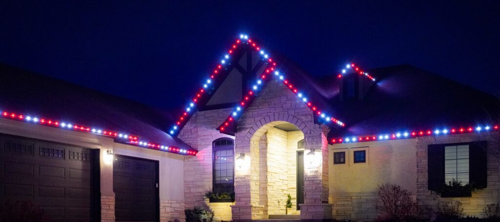 Home with cream colored stone veneer decorated with red and white permanent holiday lights