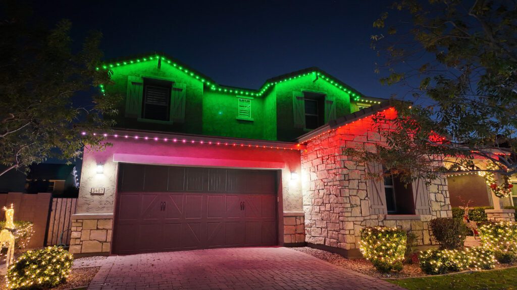 Stucco and stone home with permanent Christmas lighting in red, green, and purple lights