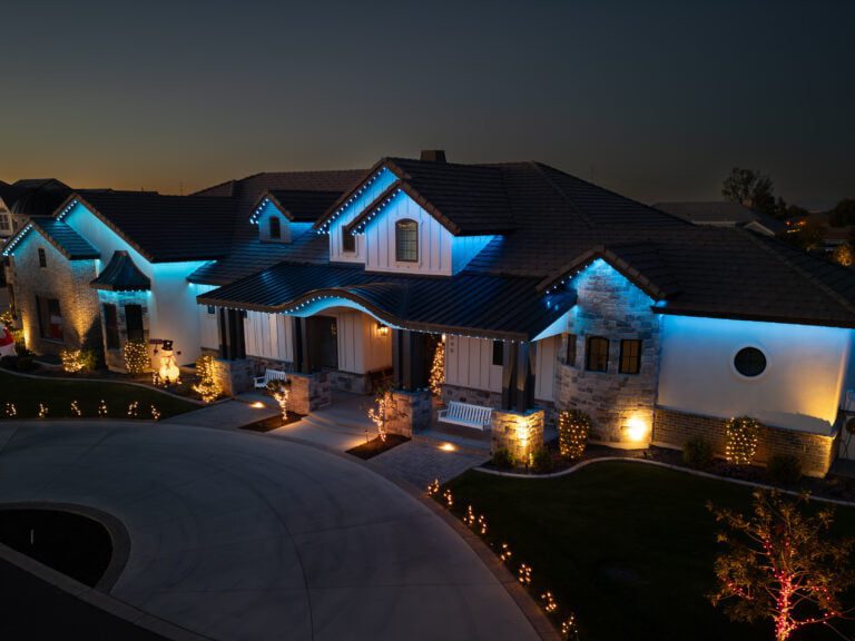 House with permanent blue holiday lights highlighting the roofline and architectural details.