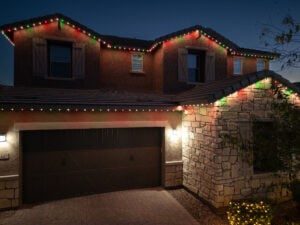 Stucco and stone home with permanent Christmas lighting in red green and warm white lights