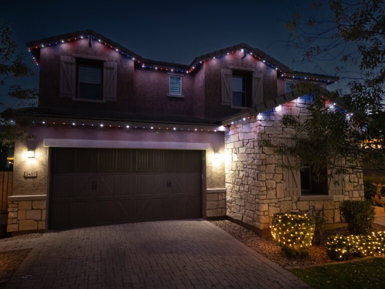 Stucco and stone home with permanent trim lighting in bright white and dimmed red and blue lights