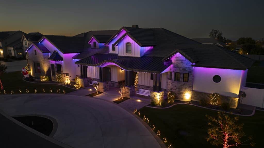 White home with purple and pink accent lighting outlining the roofline and gables