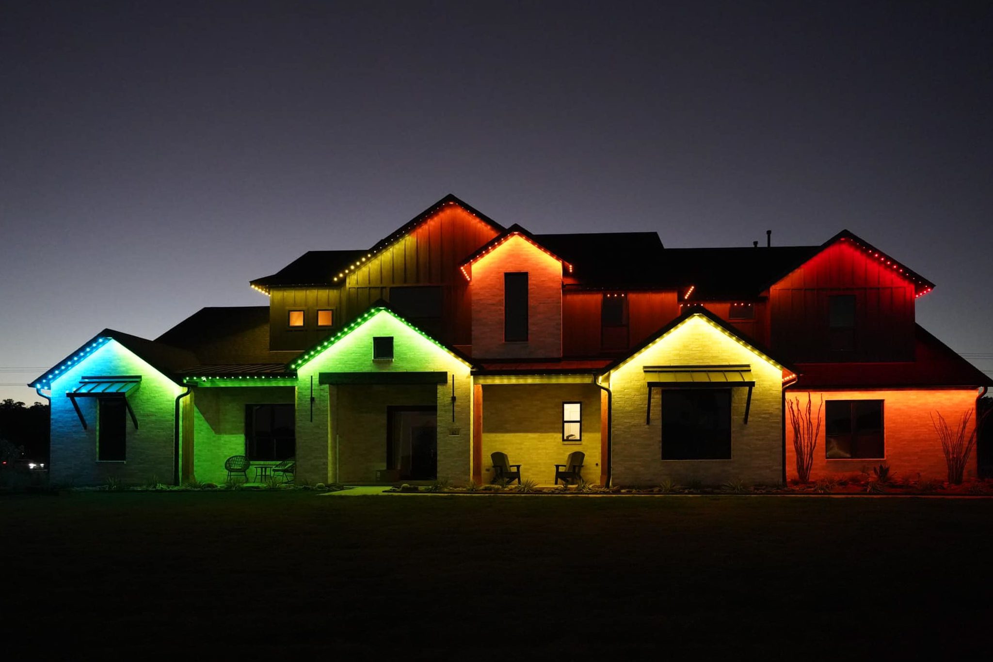 Colorful house lit up with permanent holiday lights showcasing vibrant hues of blue, green, orange, and red.