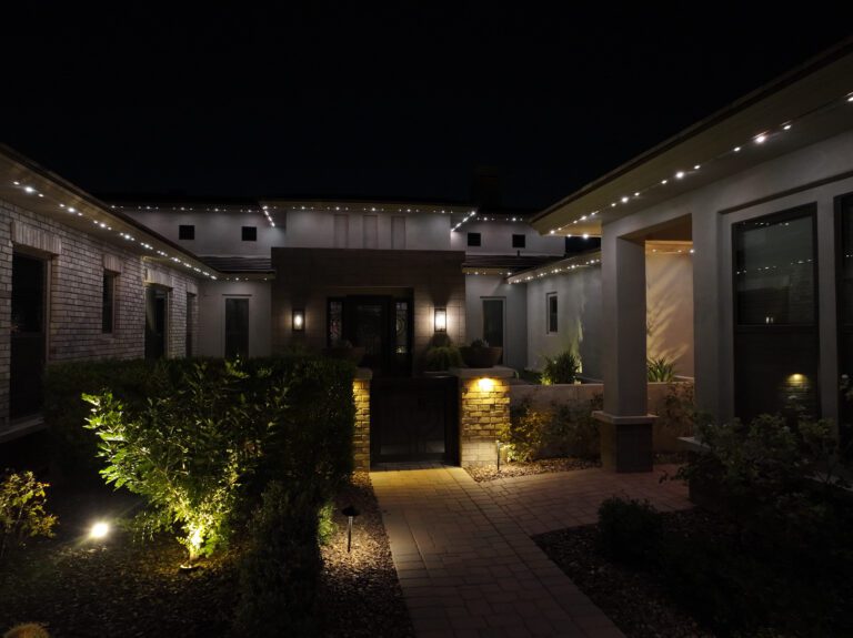 Modern Phoenix home with permanent LED trim lighting installed along rooflines and landscape lighting illuminating the entry courtyard at night