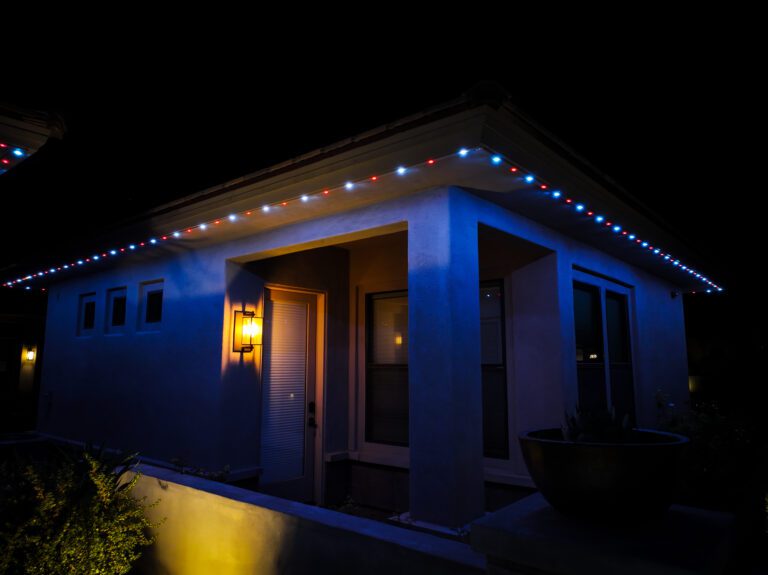 Permanent smart roofline lighting installed on a modern Phoenix home with red and white accent LEDs at night