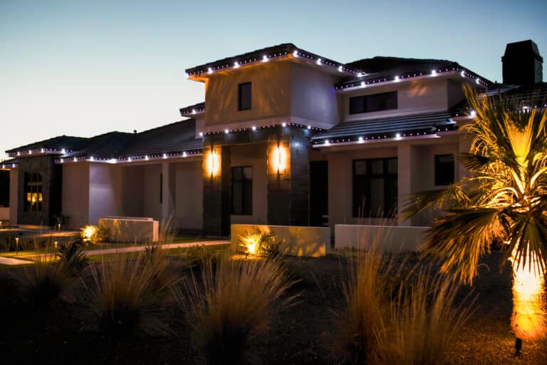 Modern Arizona home featuring permanent LED trim lighting along rooflines with accent and landscape lighting at dusk