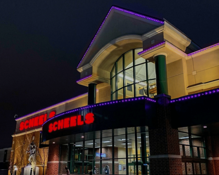 Retail storefront with permanent purple LED trim lighting outlining rooflines and architectural details at night