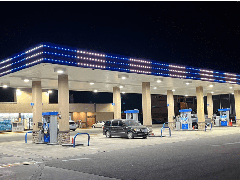 Gas station canopy with permanent LED trim lighting in blue and white outlining roofline at night
